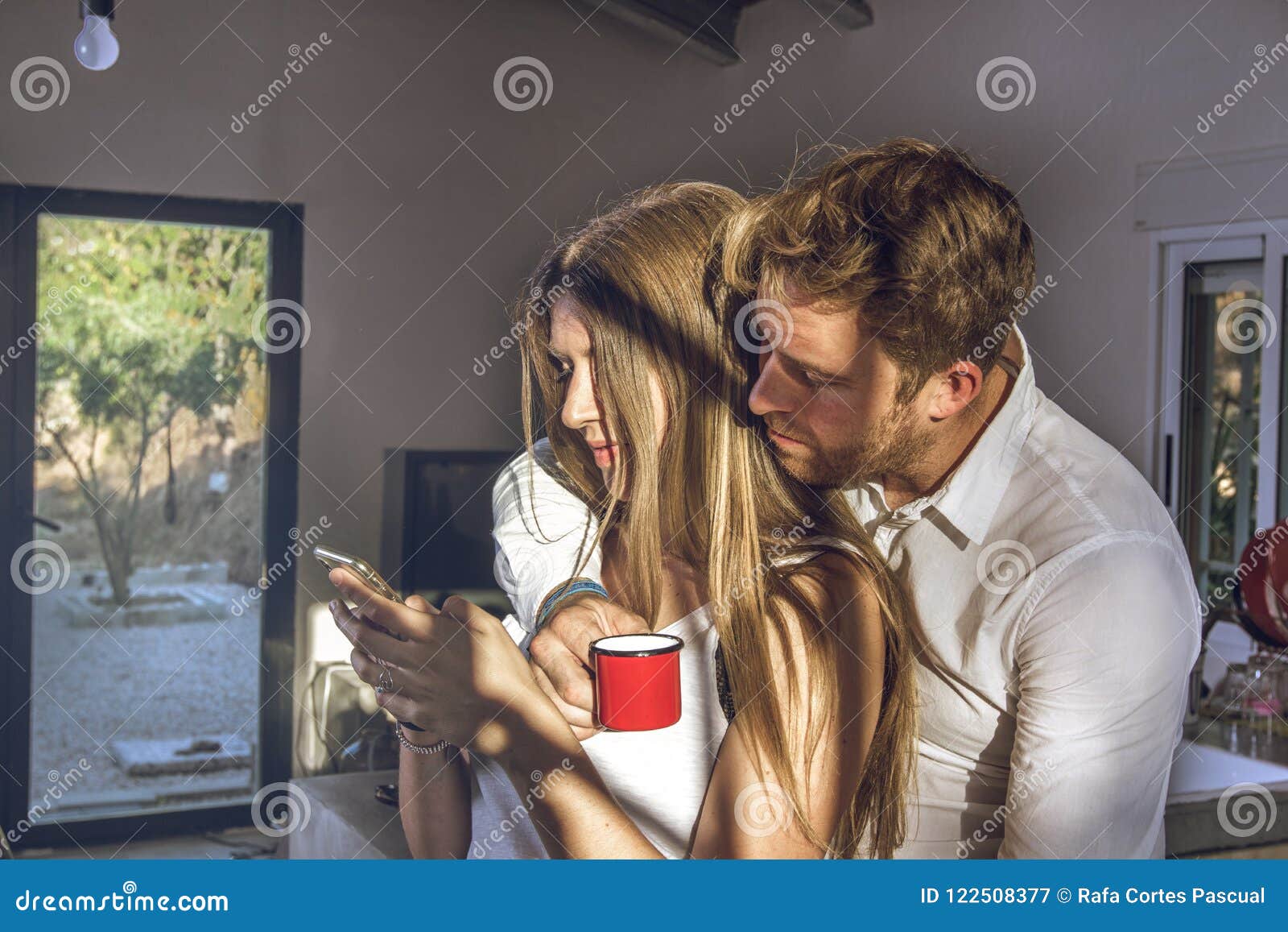 guy and girl looking at their cell phones at home. couple of guy and girl looking at their cell phone