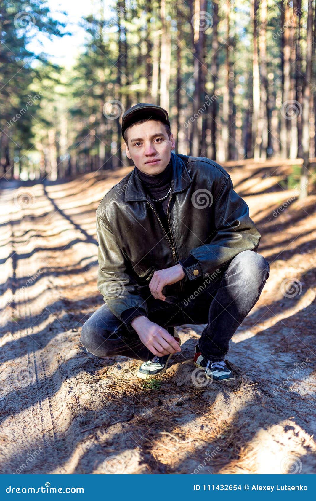 A Guy in a Leather Jacket and Cap on a Road in a Pine Forest Stock ...