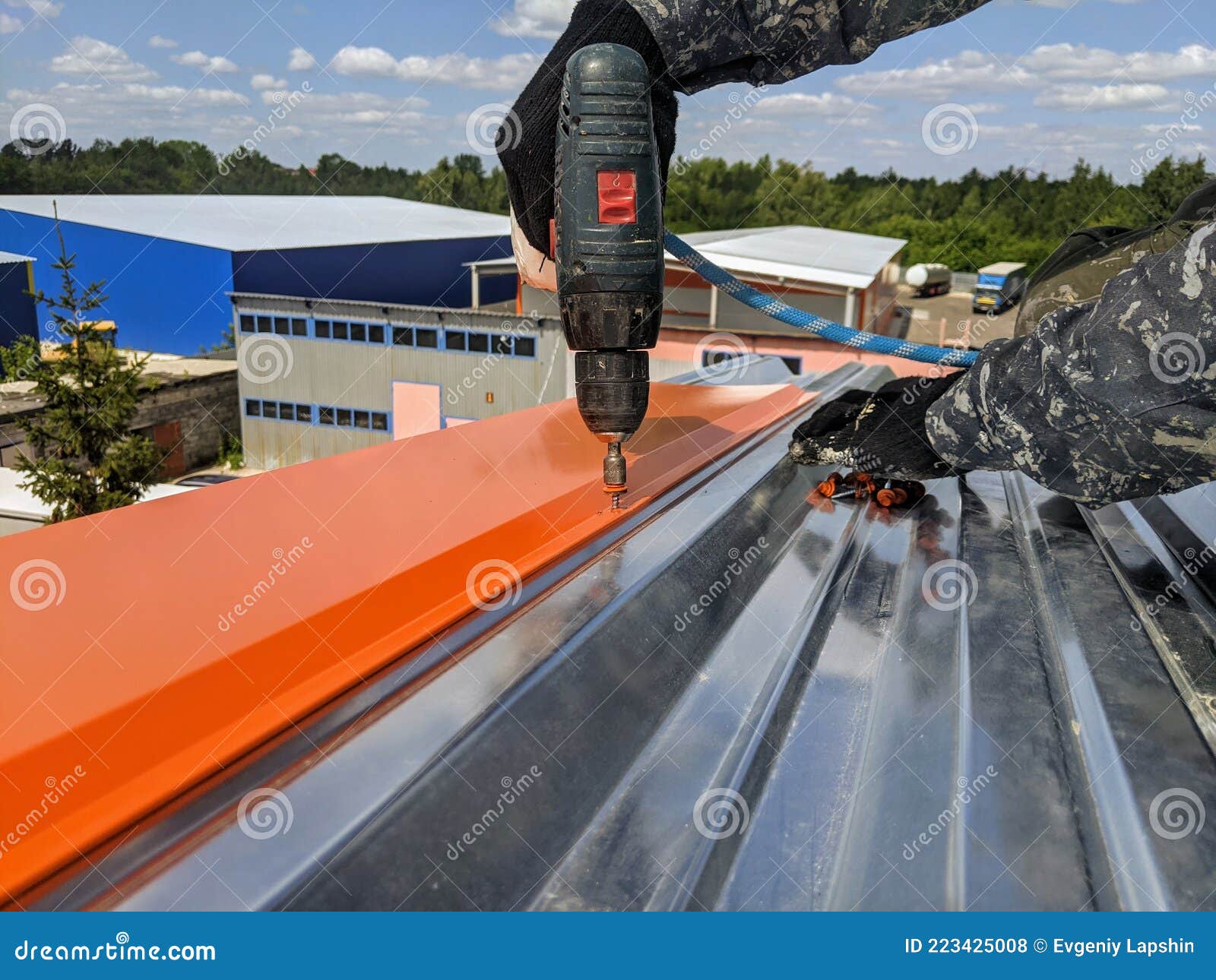 The Guy Performs Roofing Work on the Roof of the Building in the Summer on a Hot Sunny Day Stock