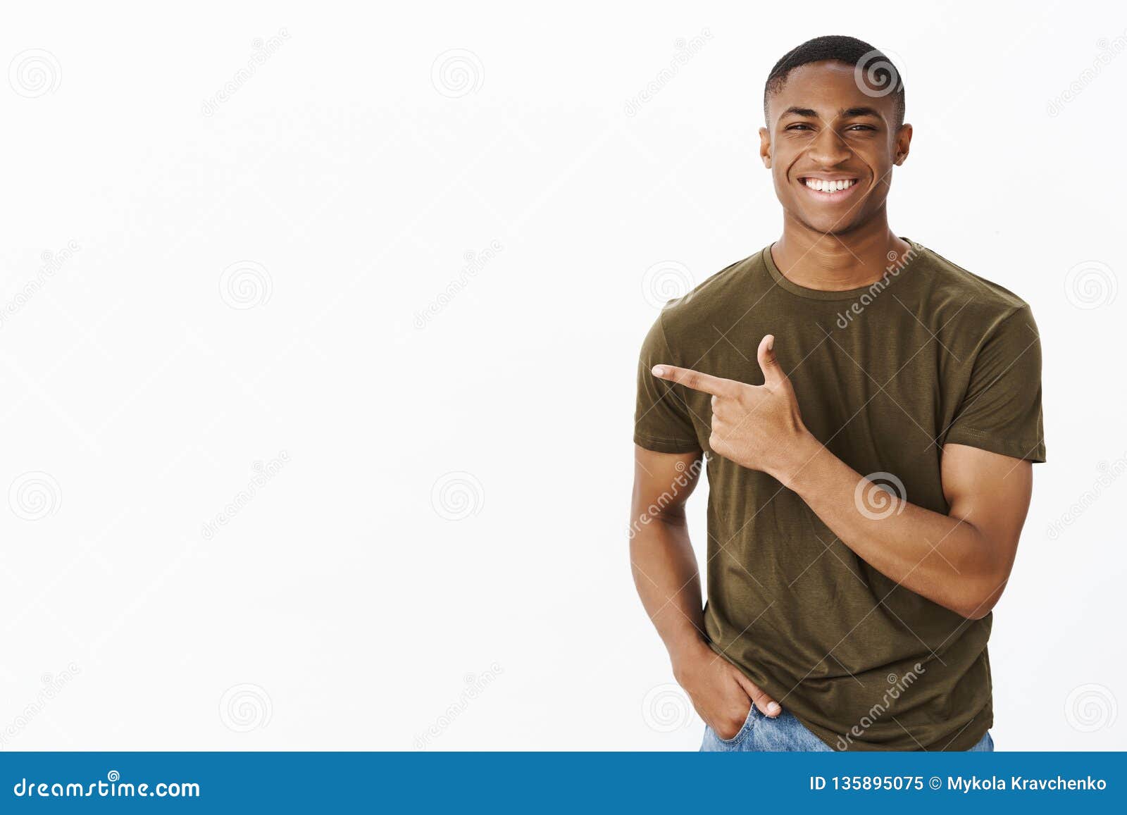 guy presenting new copy space to us with cheerful friendly smile holding hand in pocket pointing left, grinning having