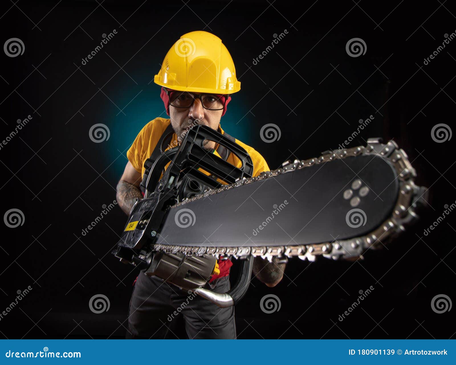A Guy in Protective Overalls with a Chainsaw on a Dark Background Stock