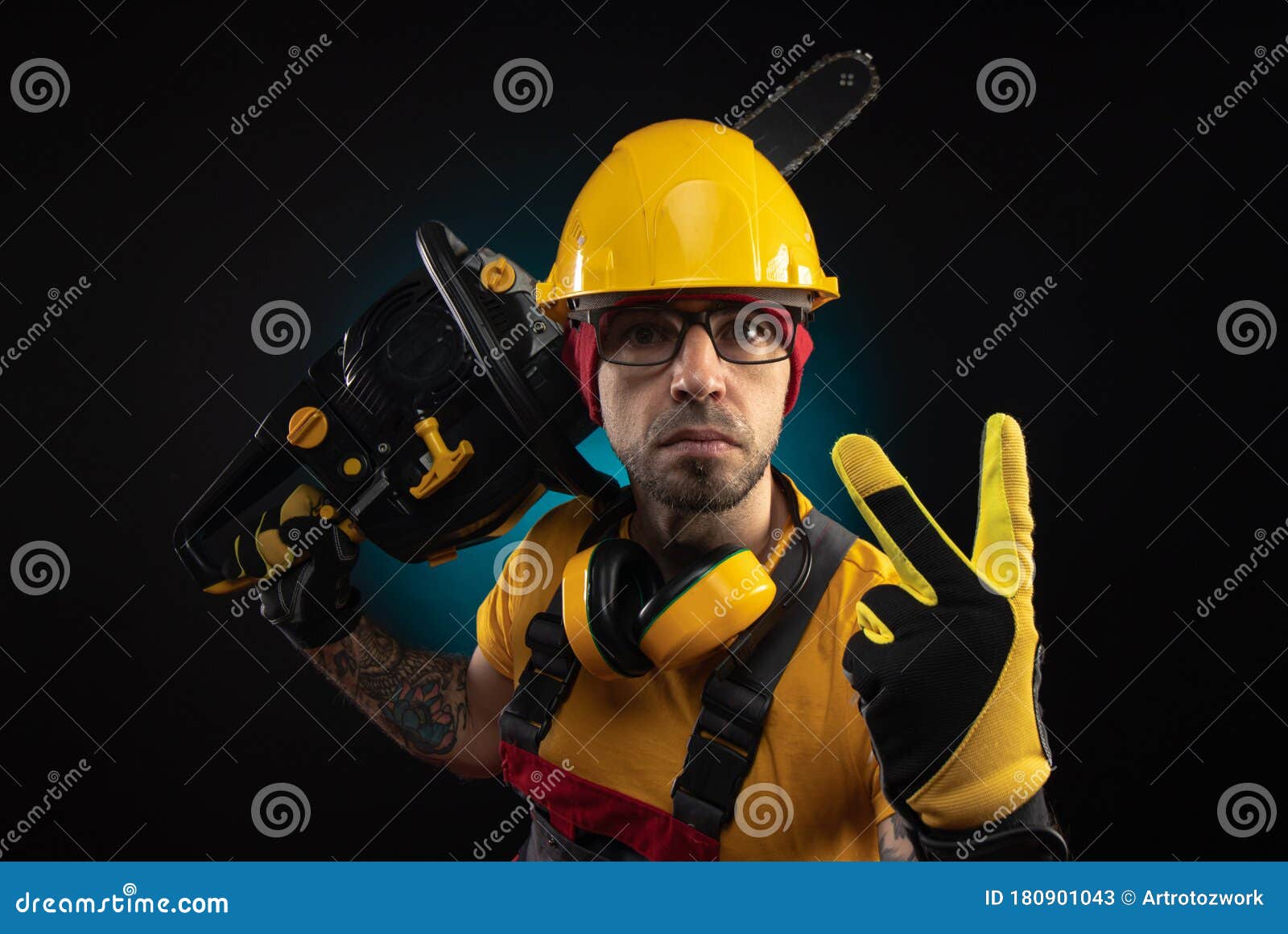 A Guy in Protective Overalls with a Chainsaw on a Dark Background Stock