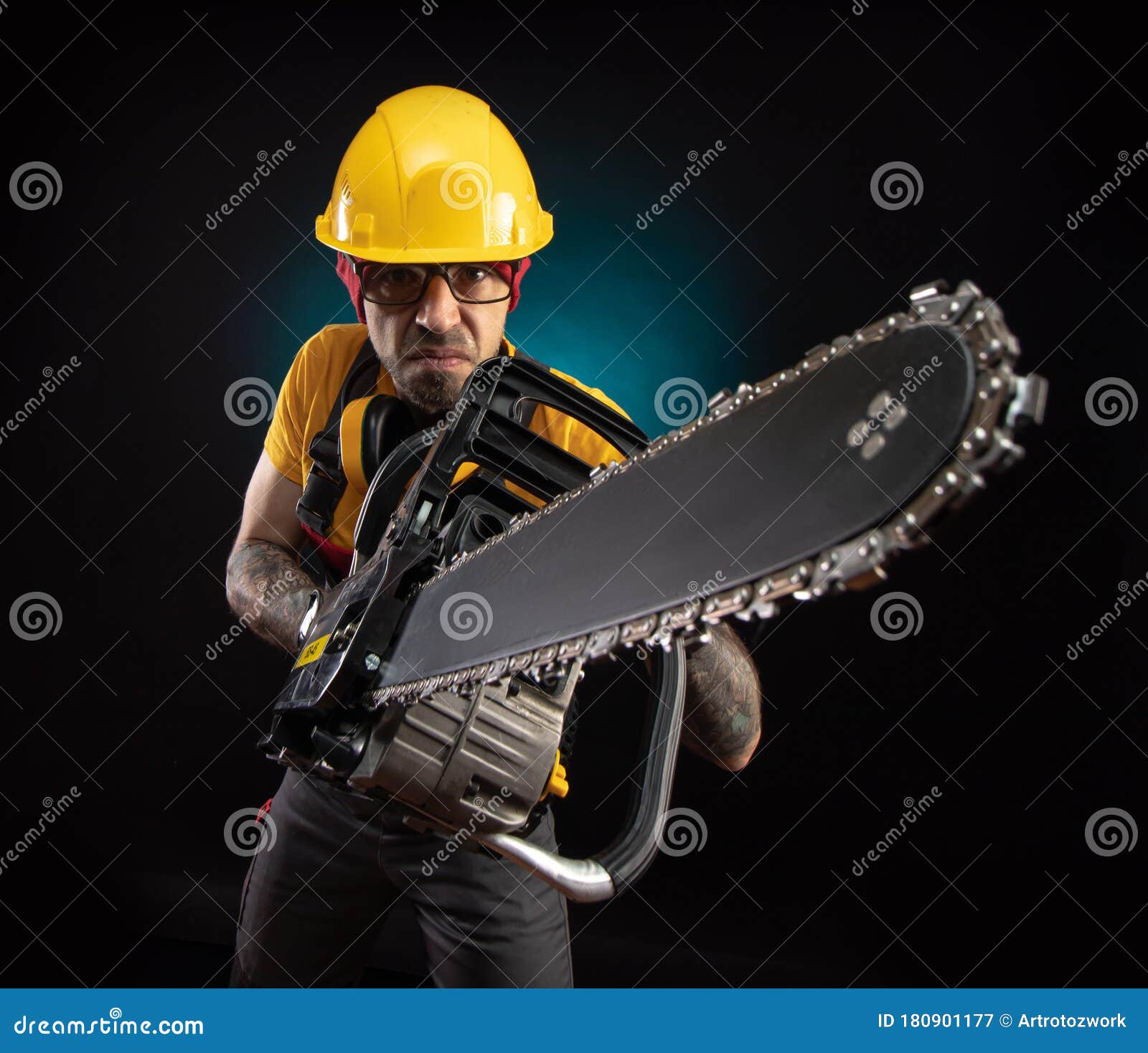 A Guy in Protective Overalls with a Chainsaw on a Dark Background Stock