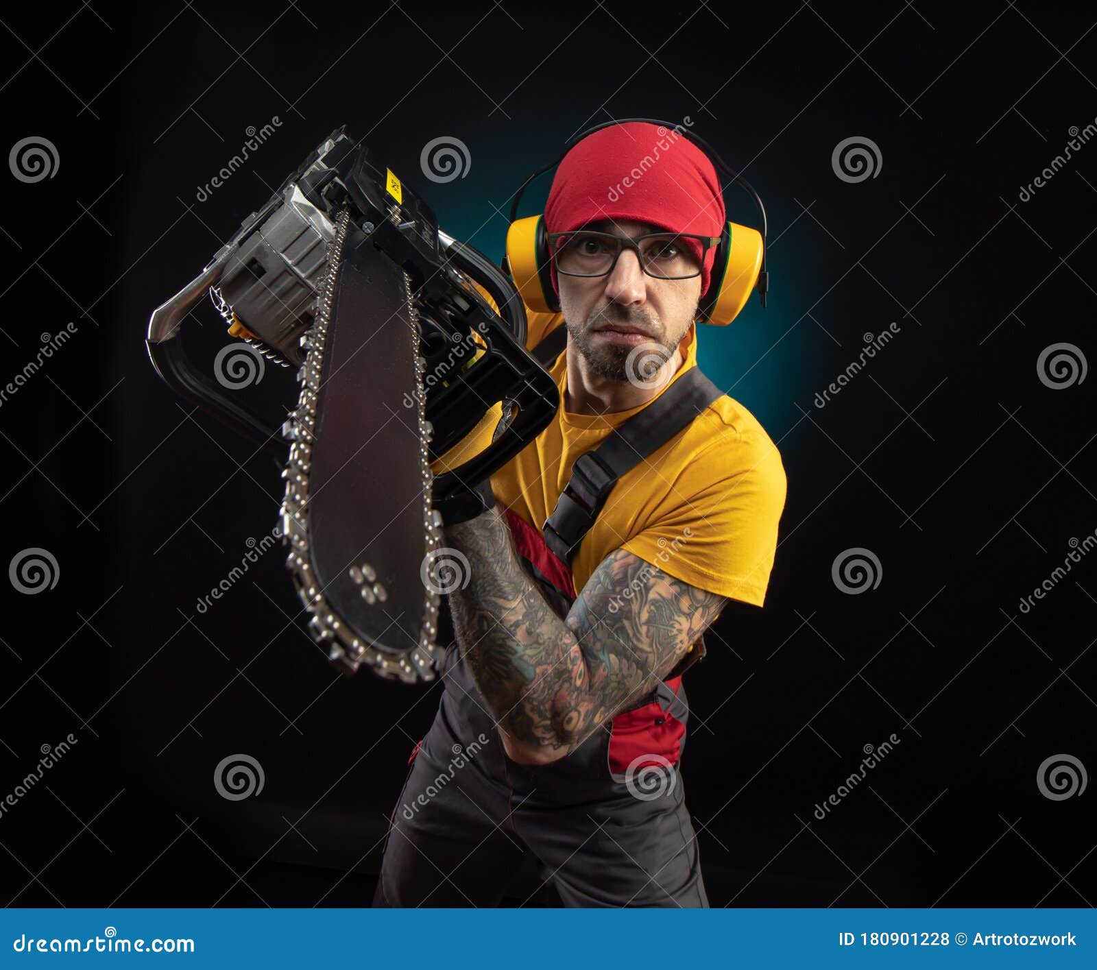 A Guy in Protective Overalls with a Chainsaw on a Dark Background Stock