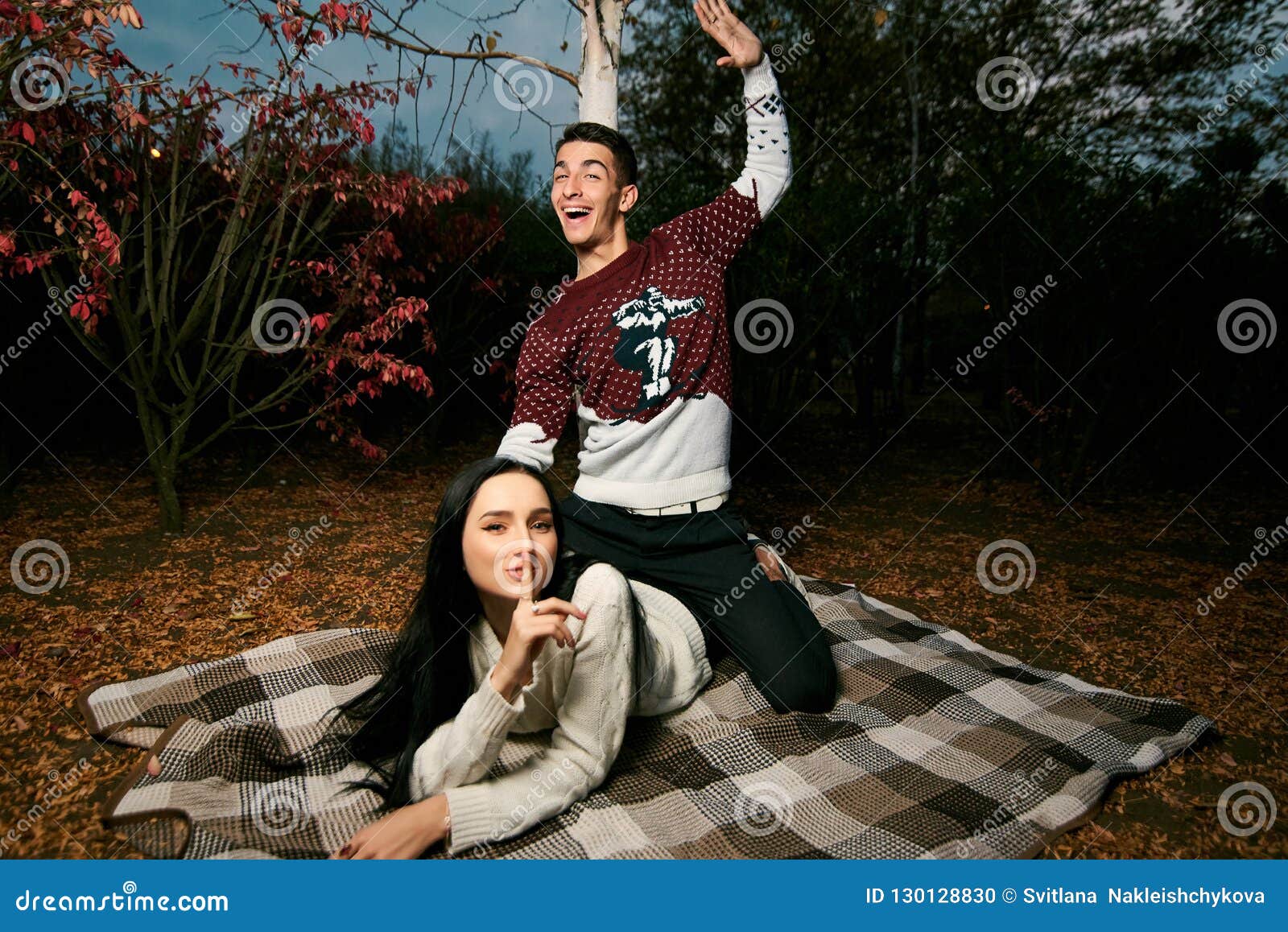 guy in a red and white sweater sits on top of a beautiful girl w