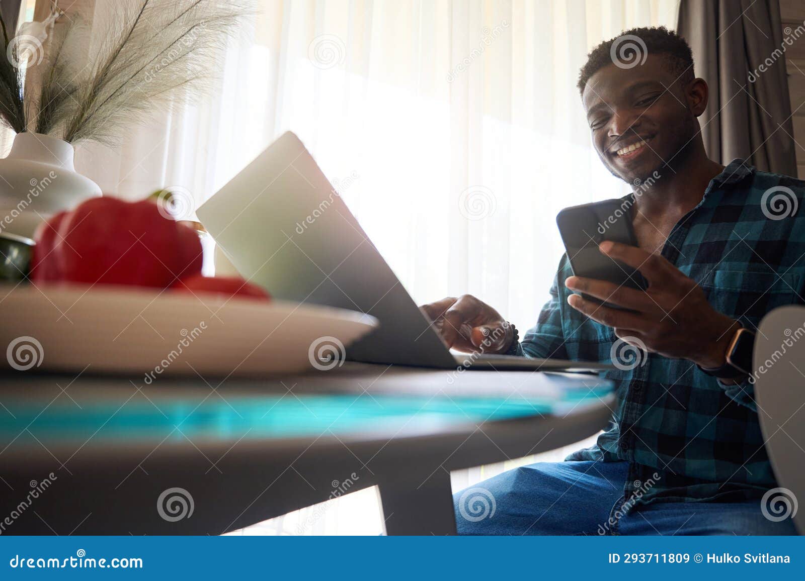 Guy Sat with Laptop and Mobile Phone at Kitchen Table Stock Image