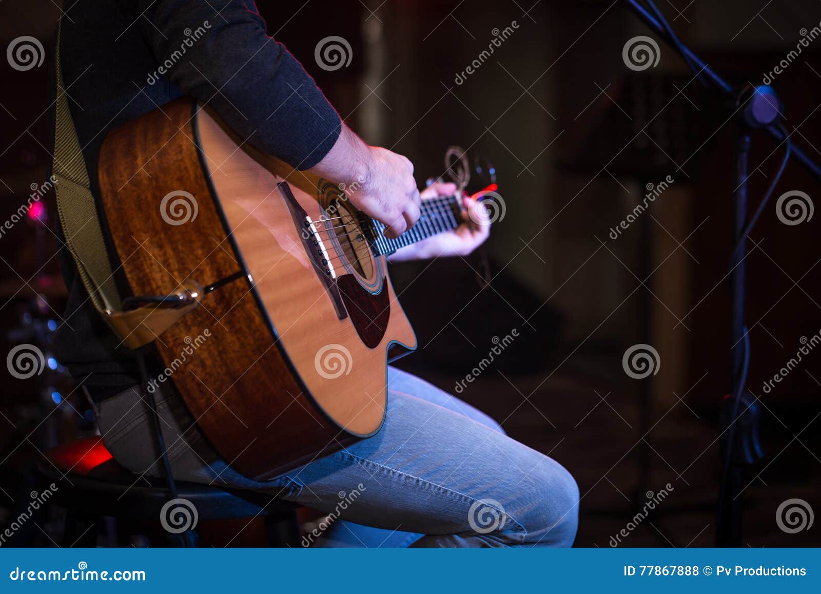 Guy Sitting in a High Chair and Playing Acoustic Guitar Stock Photo