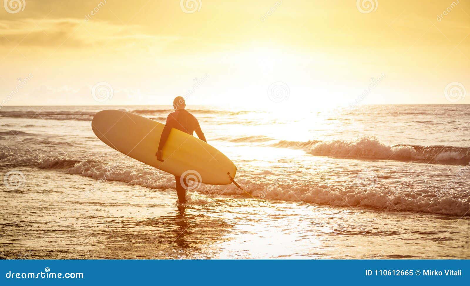 guy surfer walking with surfboard at sunset in tenerife - surf concept