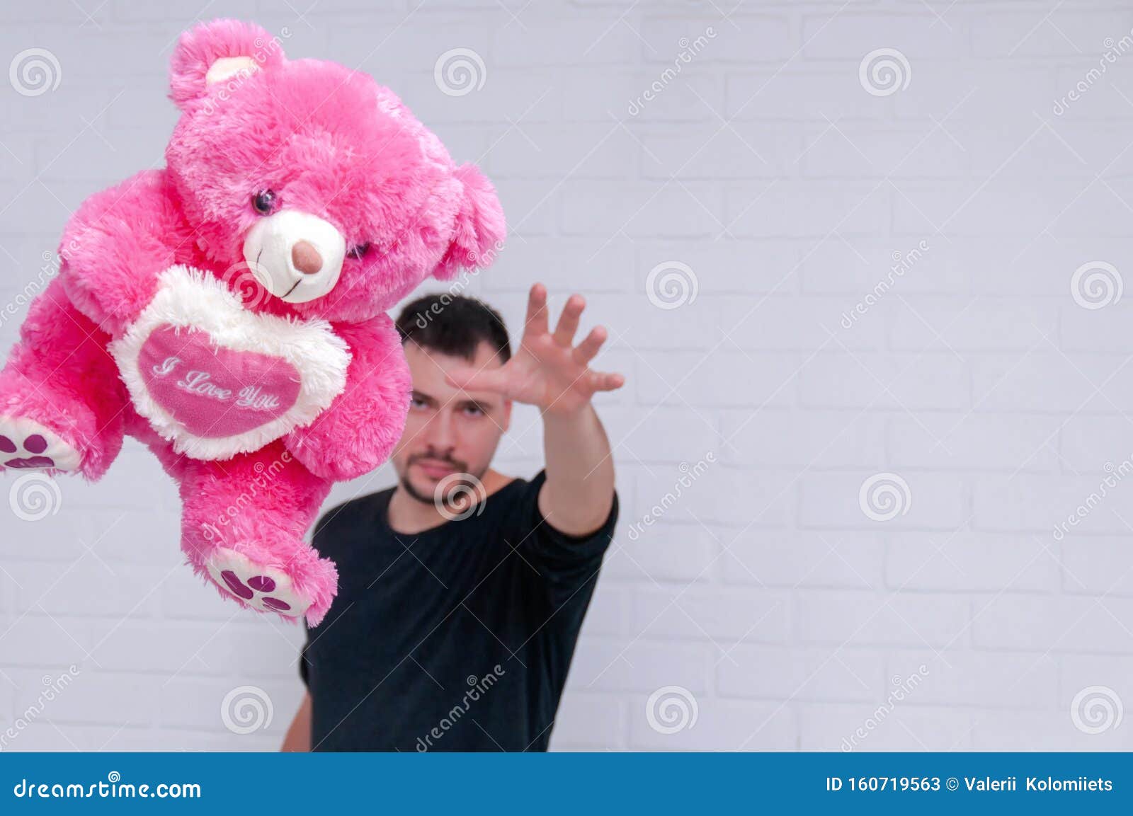 The Guy Throws a Pink Teddy Bear at the Camera on a Background of a