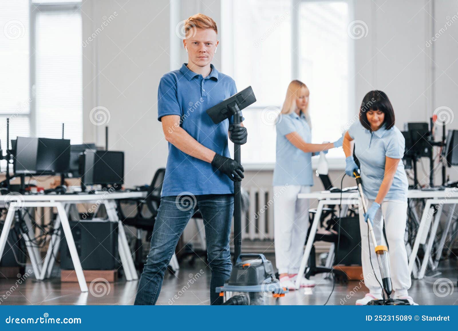 Guy with Vacuum Cleaner. Group of Workers Clean Modern Office Together