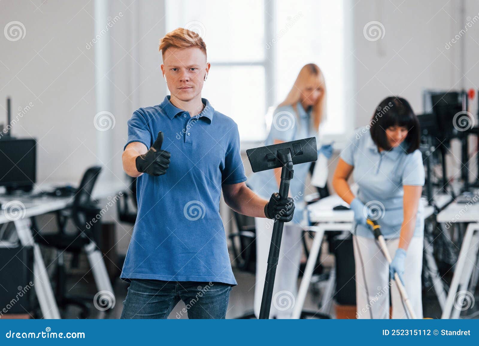 Guy with Vacuum Cleaner. Group of Workers Clean Modern Office Together