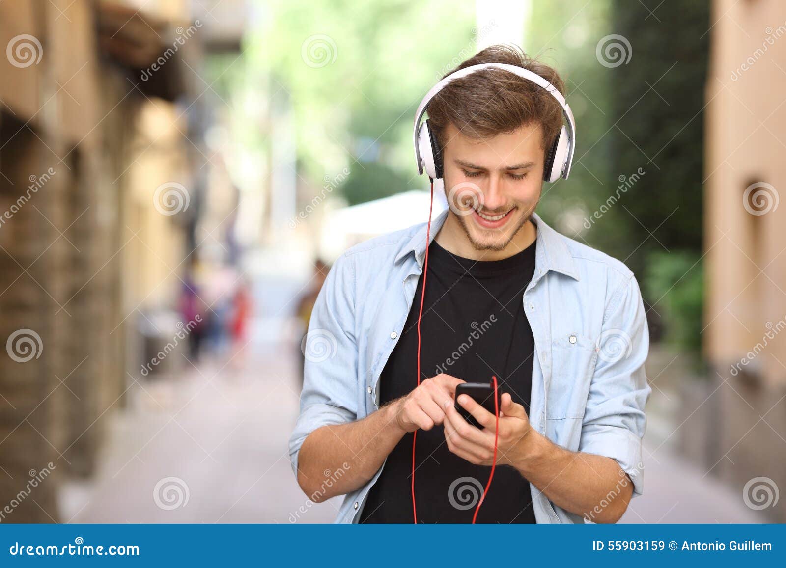 guy walking and using a smart phone with headphones