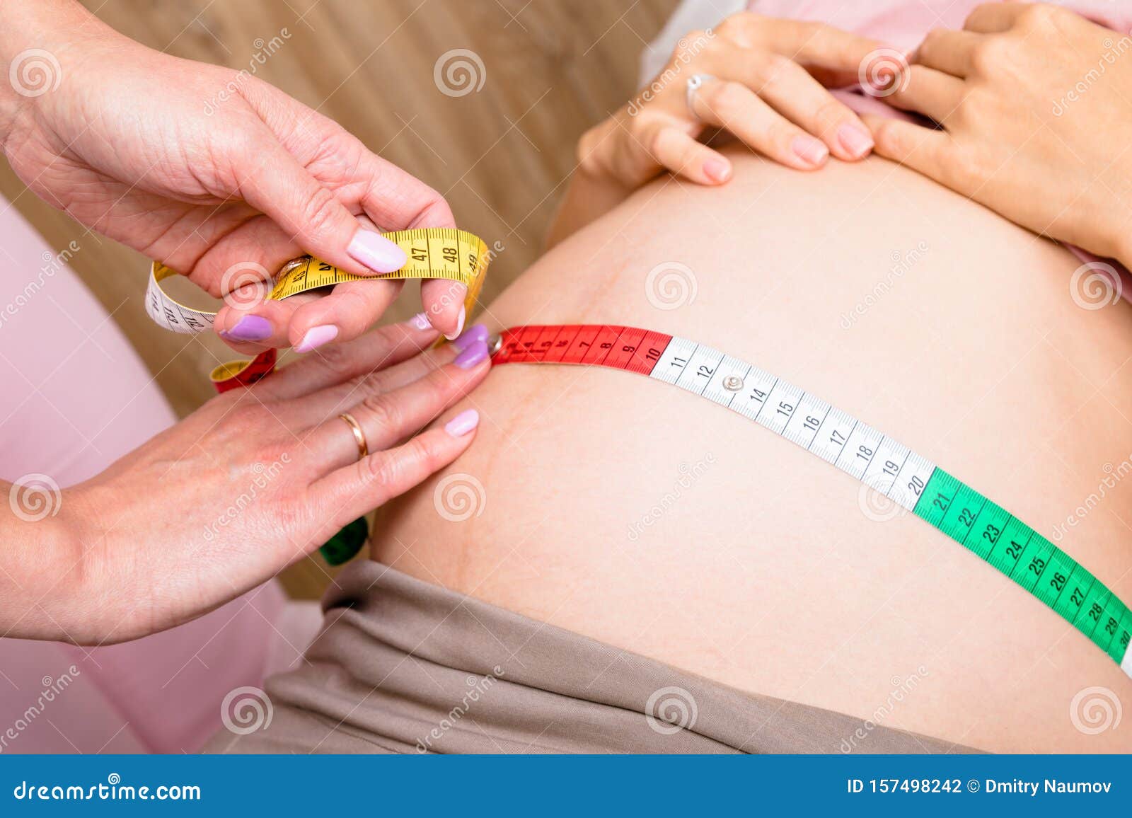 pregnant woman measuring her belly. Closeup female pregnant belly