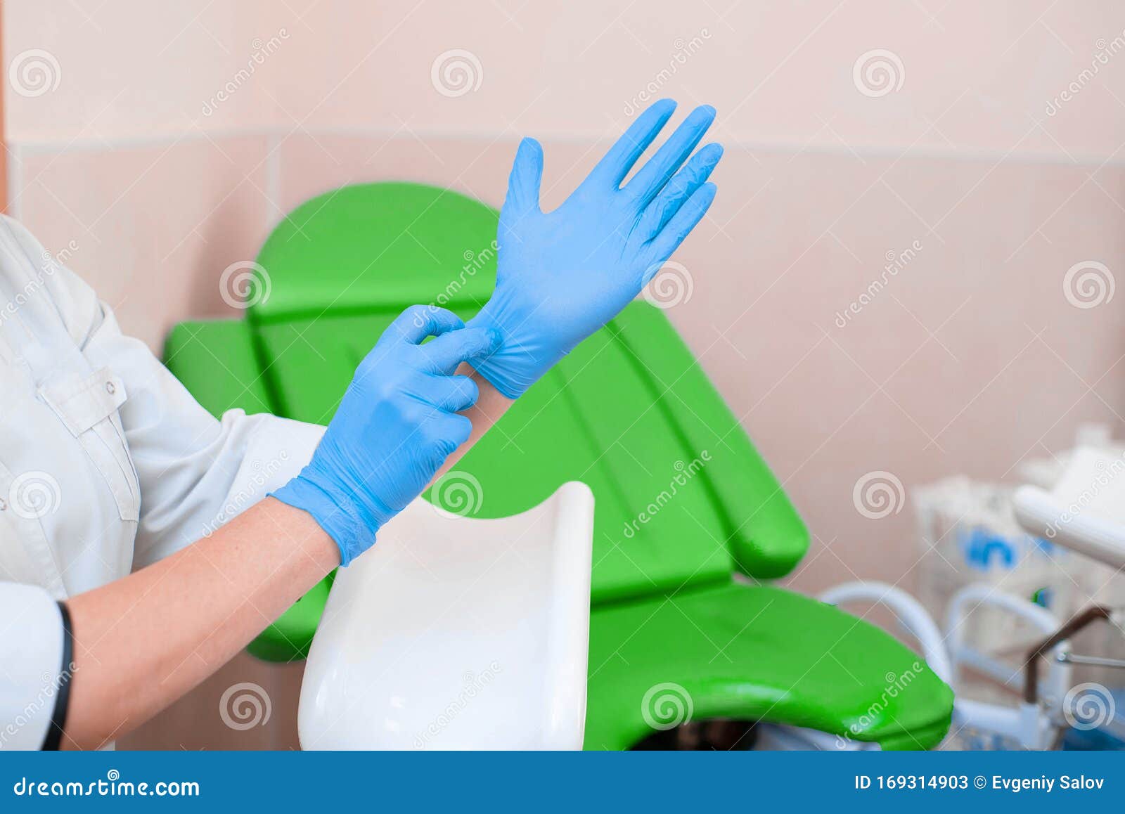 gynecologist puts on gloves on the background of a gynecological chair. medical examination