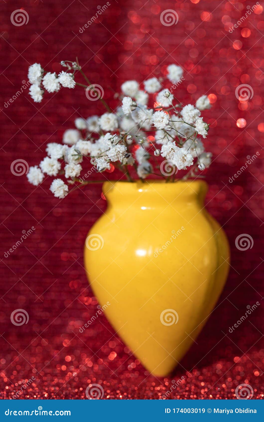 gypsophila flowers in a yellow vase on a red background.