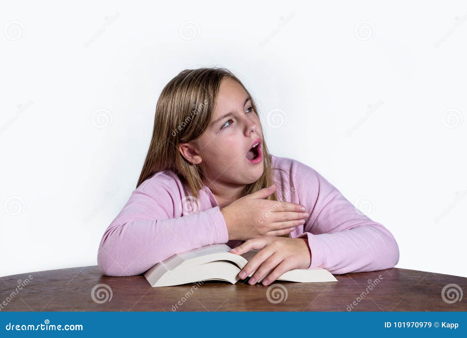 Gähnendes Mädchen mit Buch auf weißem Hintergrund. Gähnendes Mädchen am Schreibtisch mit einem Buchlernen auf einem weißen Hintergrund