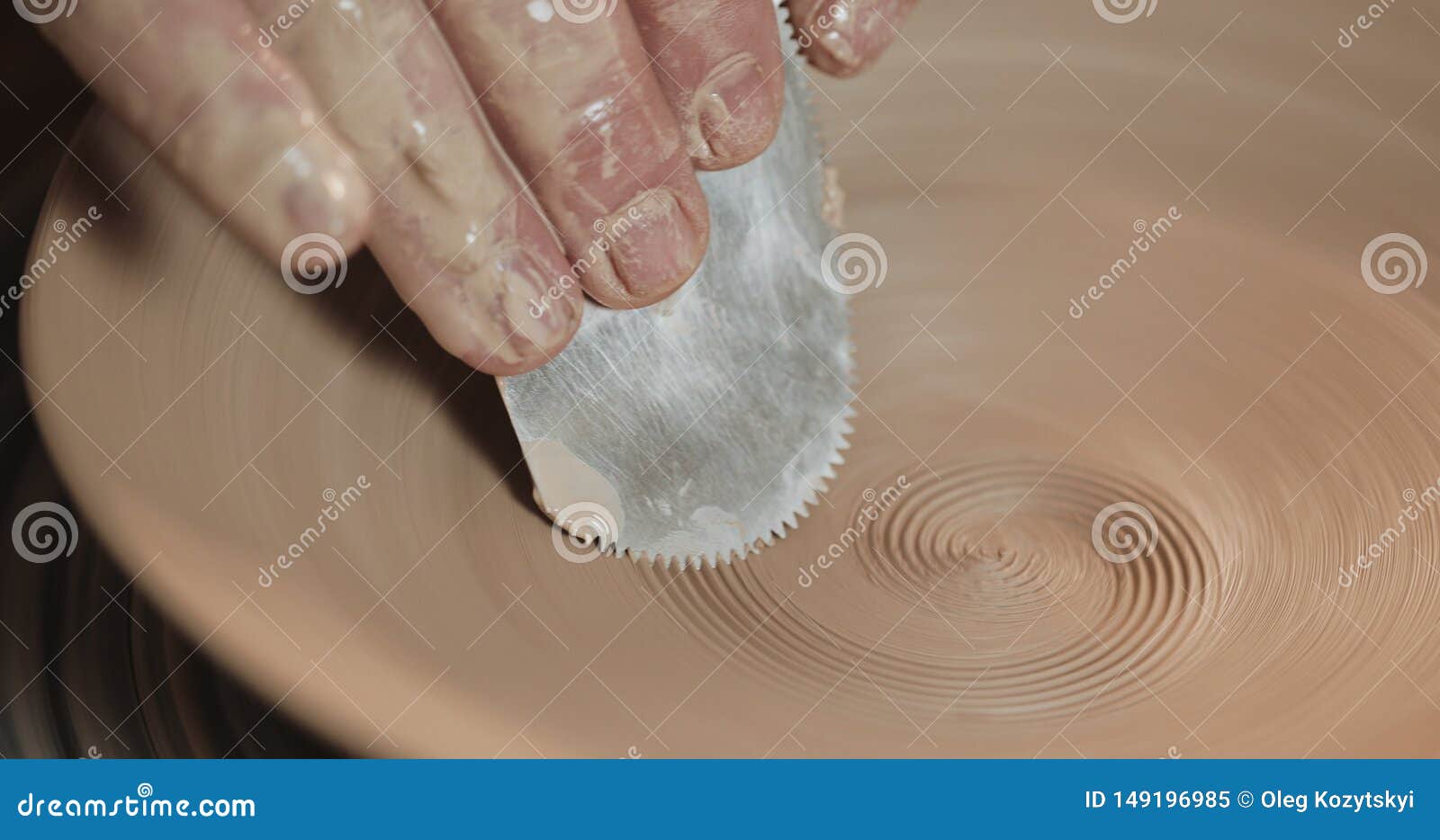 Hands working on pottery wheel with professional tools, shaping a relief on a clay plate. Potter at work, close up. Handmade, craft. White clay.