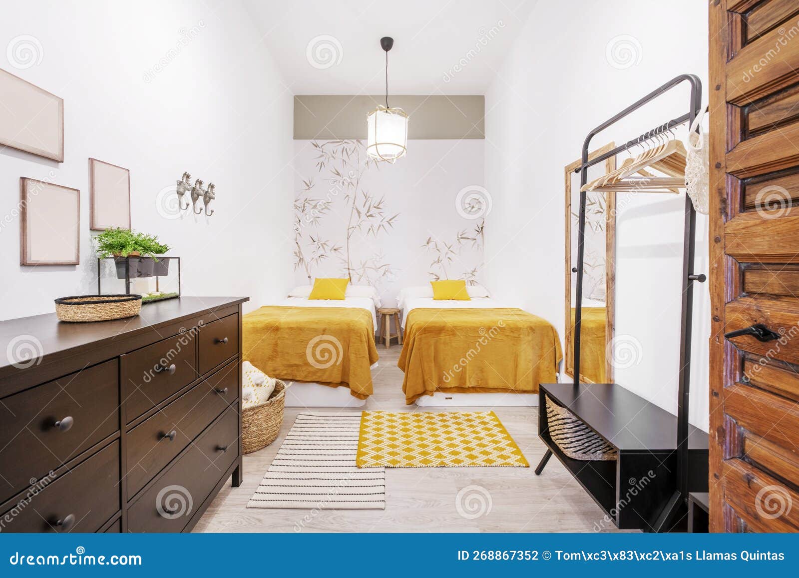 Habitación Con Camas Individuales Separada Por Un Taburete De Madera Con  Mantas Color Mostaza Y Una Cómoda Negra Con Cajones Foto de archivo -  Imagen de doméstico, hermoso: 268867352