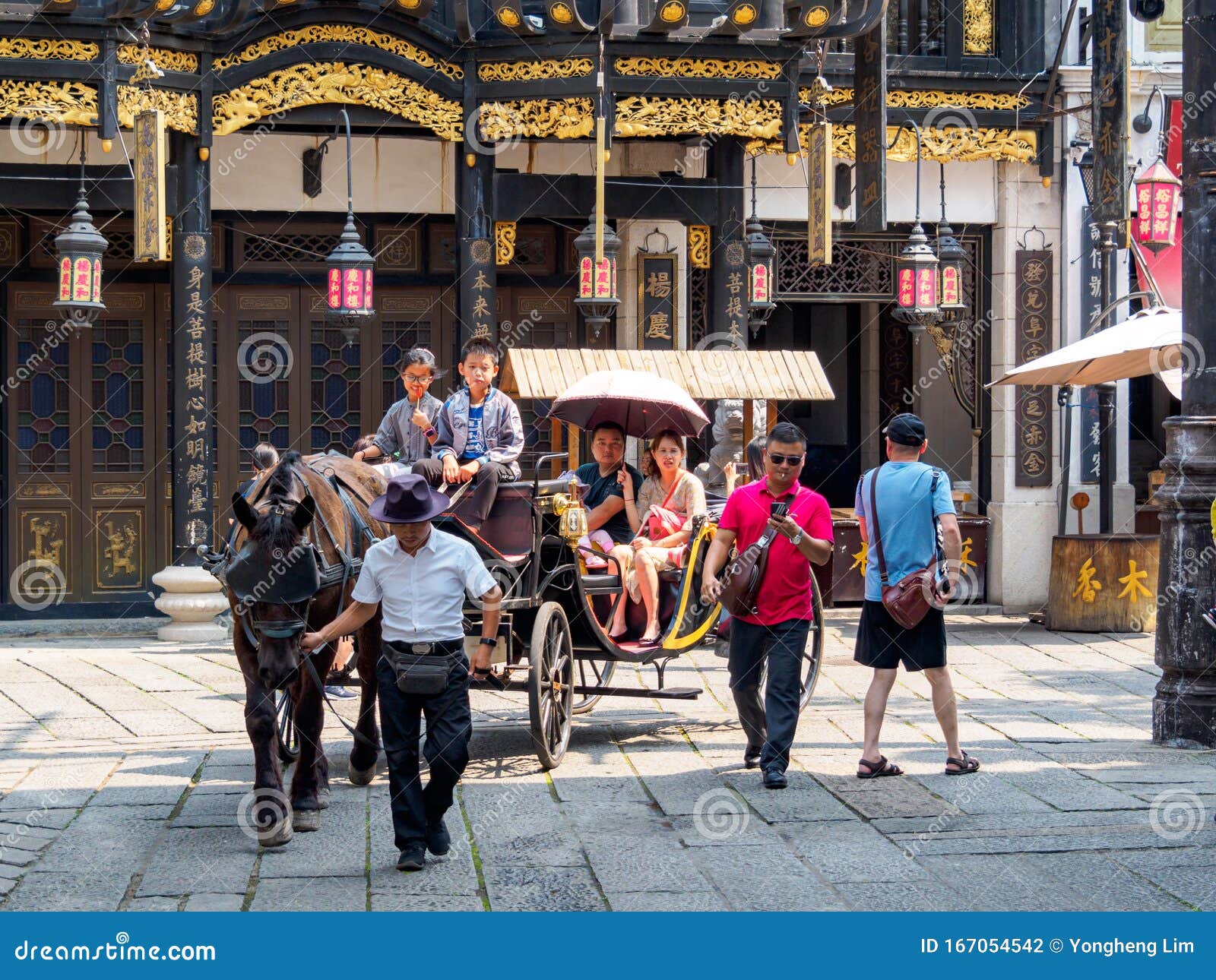 HAINAN, CHINA - 3 DE MAYO DE 2019 - La familia asiática china toma un paseo con buggy en la ciudad de cine Feng Xiao Gang en Hain. HAINAN, CHINA - 3 DE MAYO DE 2019 - Una familia asiática china da un paseo en un buggy a caballo en la ciudad de cine Feng Xiao Gang en Hainan, un popular parque temático