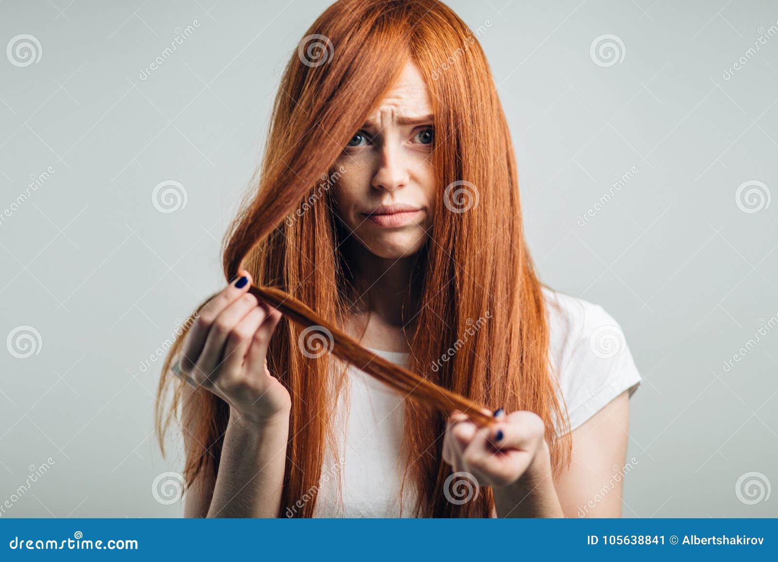 Sad Redhead Girl Holding Her Damaged Hair Looking At Camera Stock