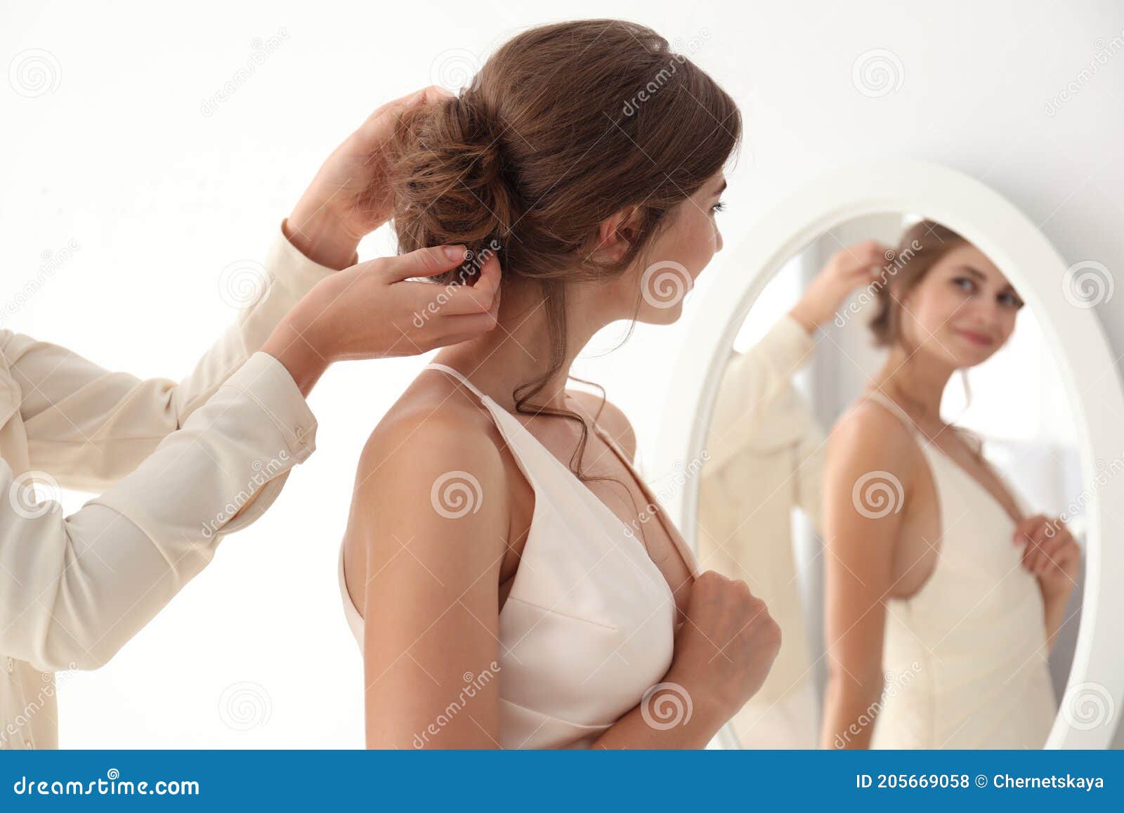 hair stylist preparing bride for her wedding indoors