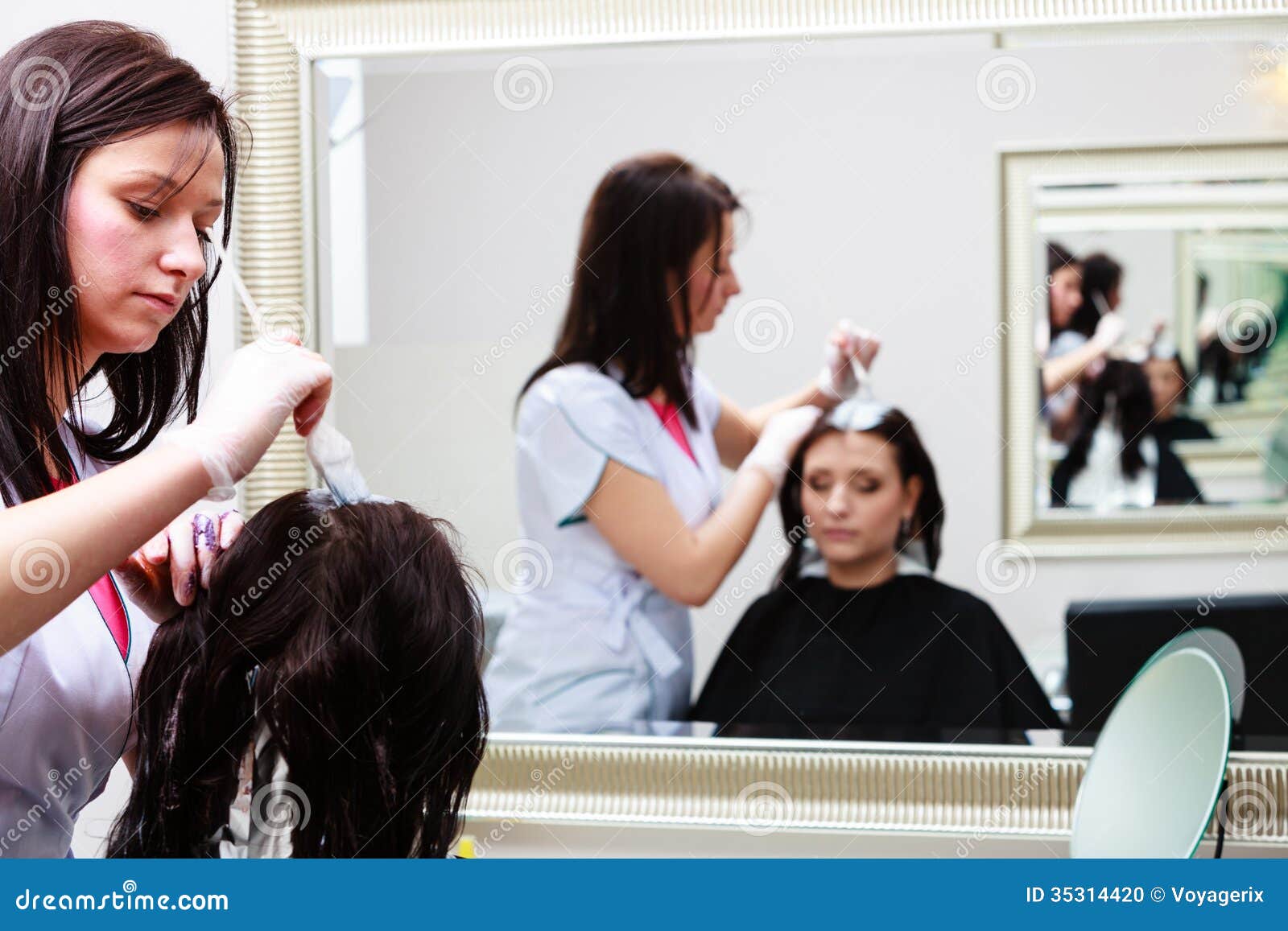 hairdresser applying color female customer at salon, doing hair dye