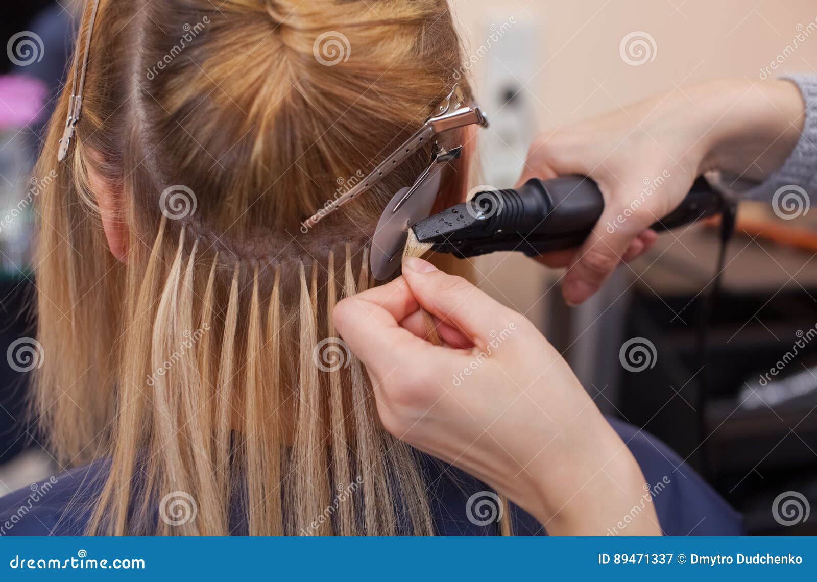 the hairdresser does hair extensions to a young girl, a blonde in a beauty salon.