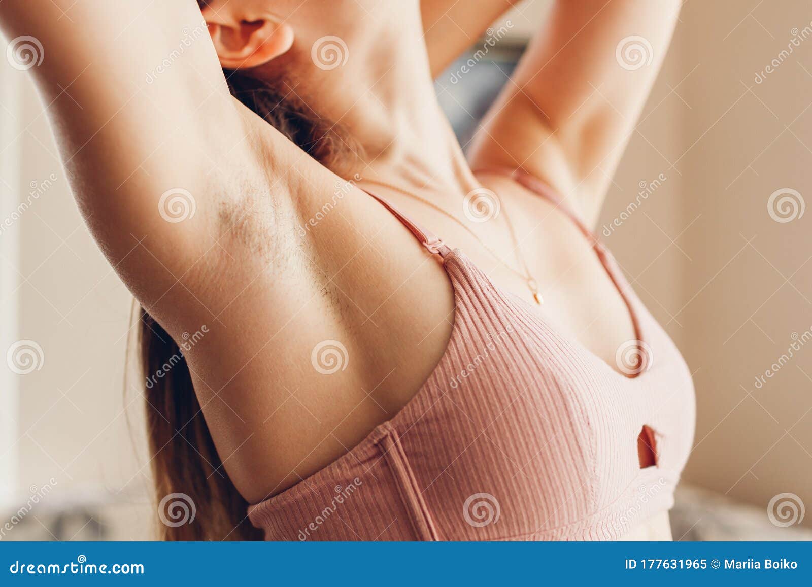 high angle view of woman in black bra cutting green plant on armpit on grey  Stock Photo