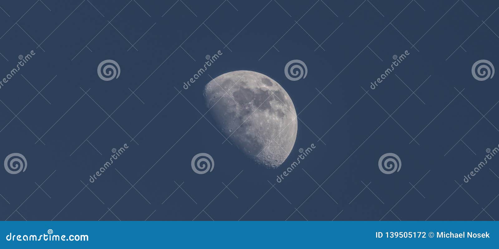 Half Blue Moon with Seas and Craters and Blue Winter Sky Stock Photo