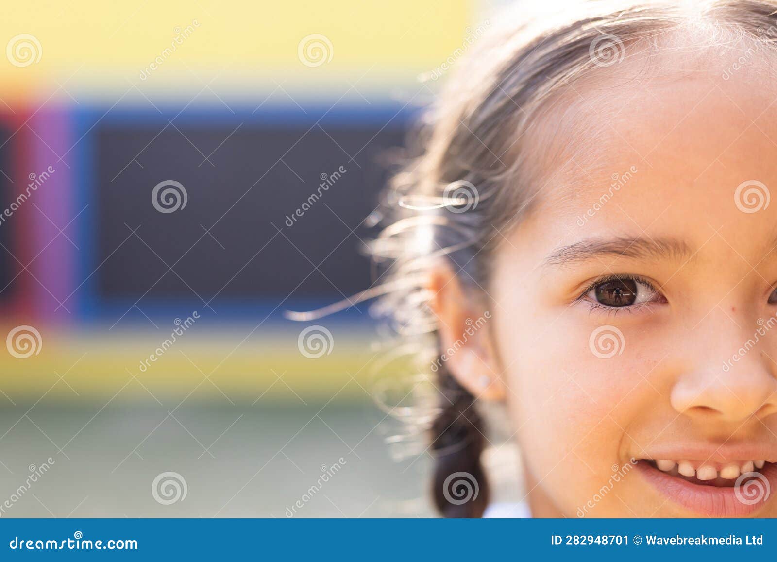 half face portrait of smiling cauasian ary schoolgirl in school playground, copy space