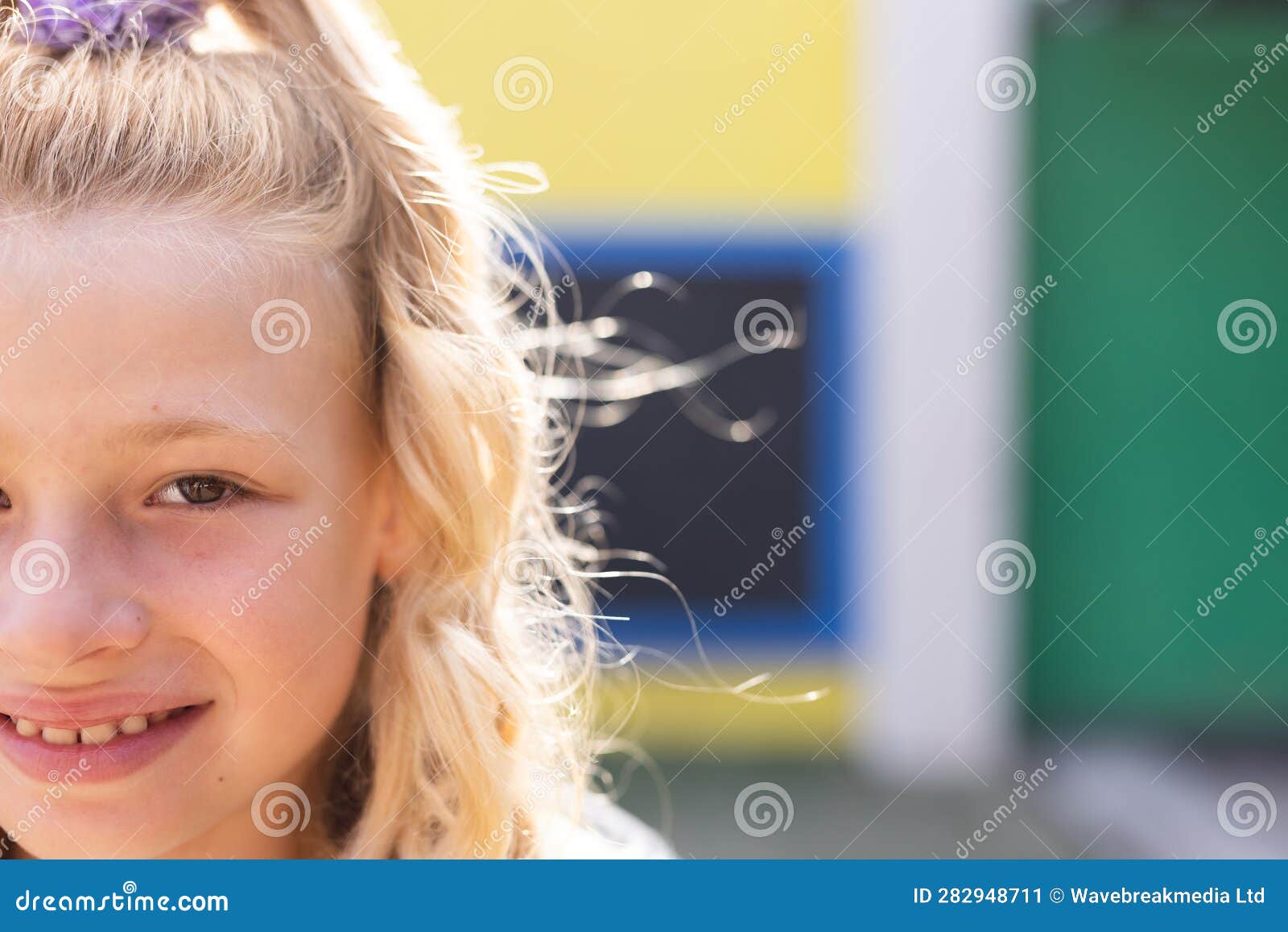 half face portrait of smiling cauasian ary schoolgirl in school playground, copy space