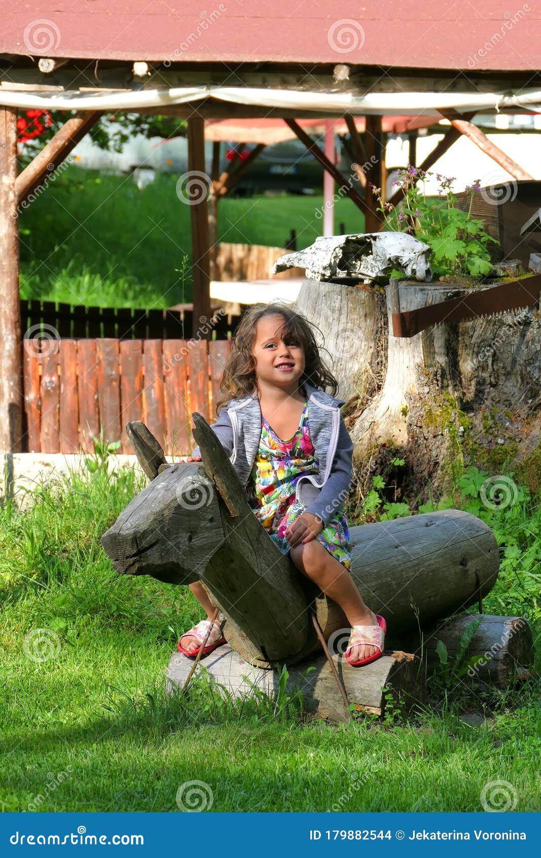 4 and a half year old girl plays happy on a wooden horse