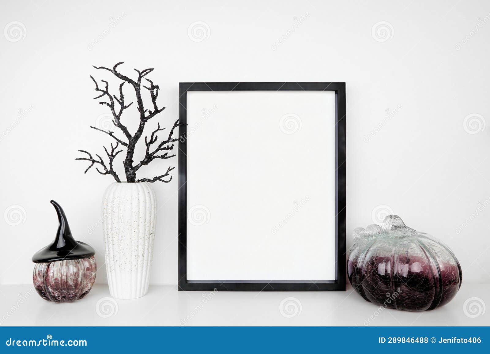 halloween mock up black frame on a white shelf with black branches and glass pumpkin decor