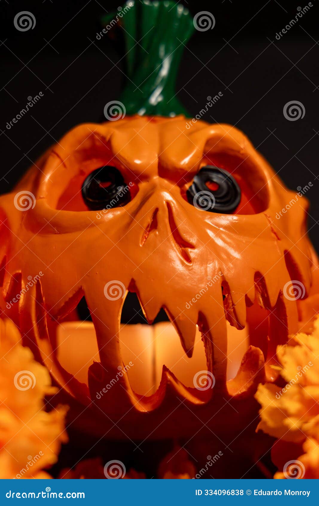 halloween pumpkin with candles and marigolds on black background