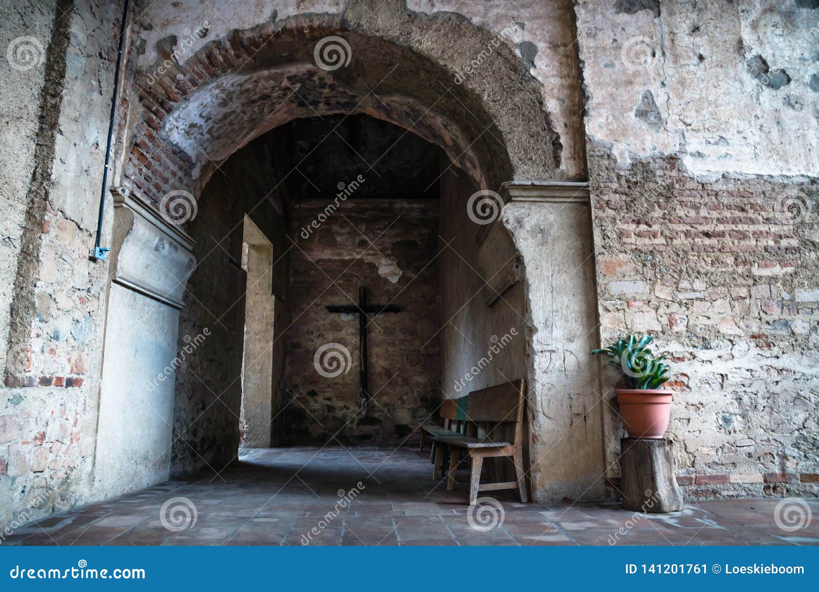 hallway of hermano pedro monestery with cross, plant and arch, antigua, guatemala