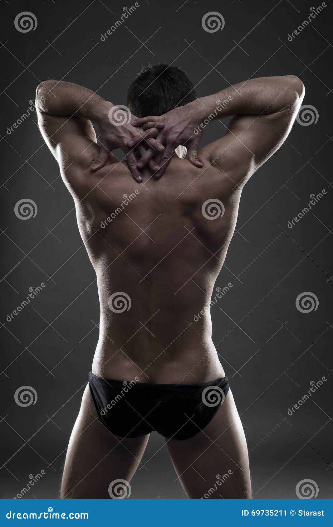 Halterofilista muscular considerável que levanta no fundo cinzento Baixo tiro chave do estúdio Corpo masculino "sexy"