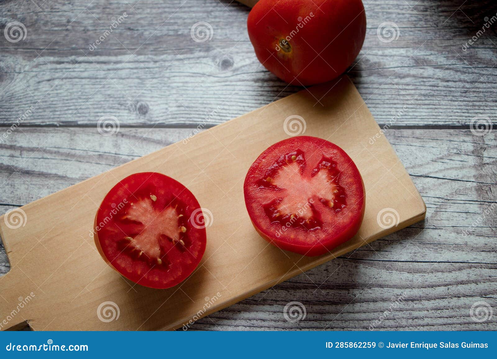 a halved tomato on a chopping board