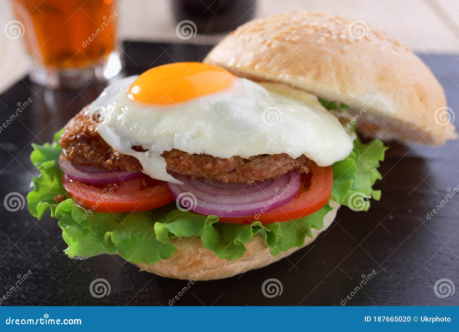 Hambúrguer com ovo frito e batata frita em um fundo preto, em um