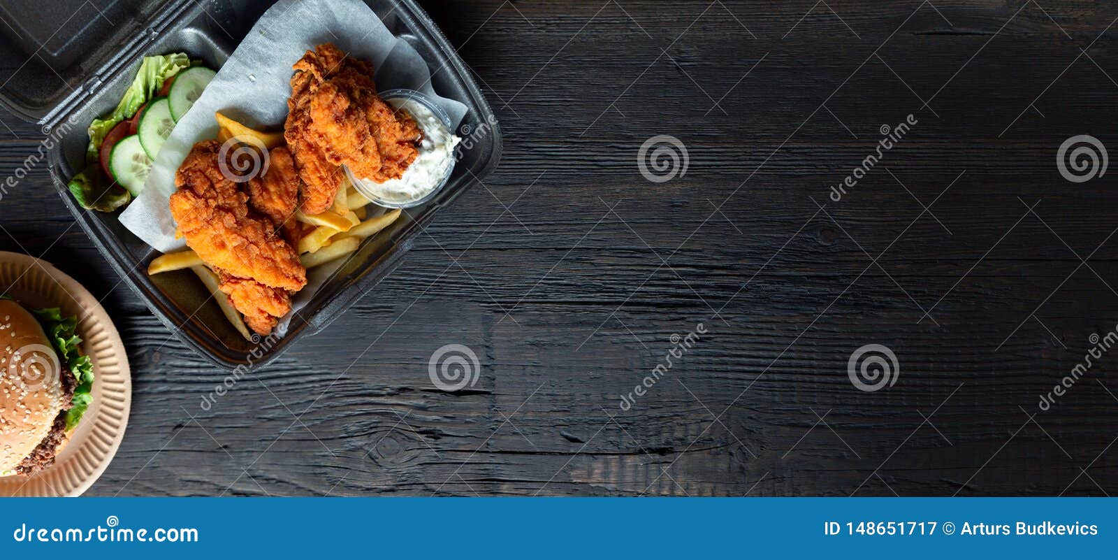 hamburger, french fries and fried chicken in takeaway containers on the wooden background. food delivery and fast food concept.