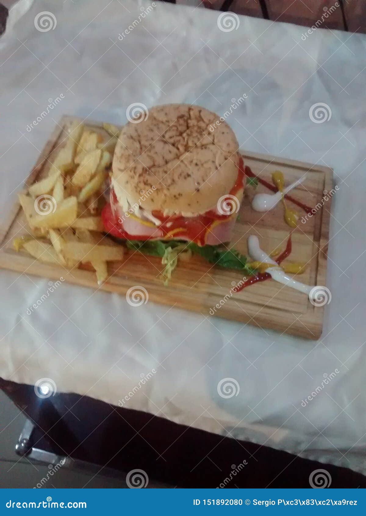 hamburger on wooden table with fried potatoes and sauces of various colors and flavors is a fast or chatarra food