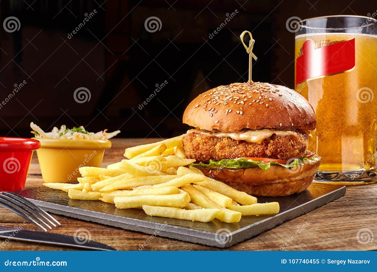 Hambúrguer com ovo frito e batata frita em um fundo preto, em um