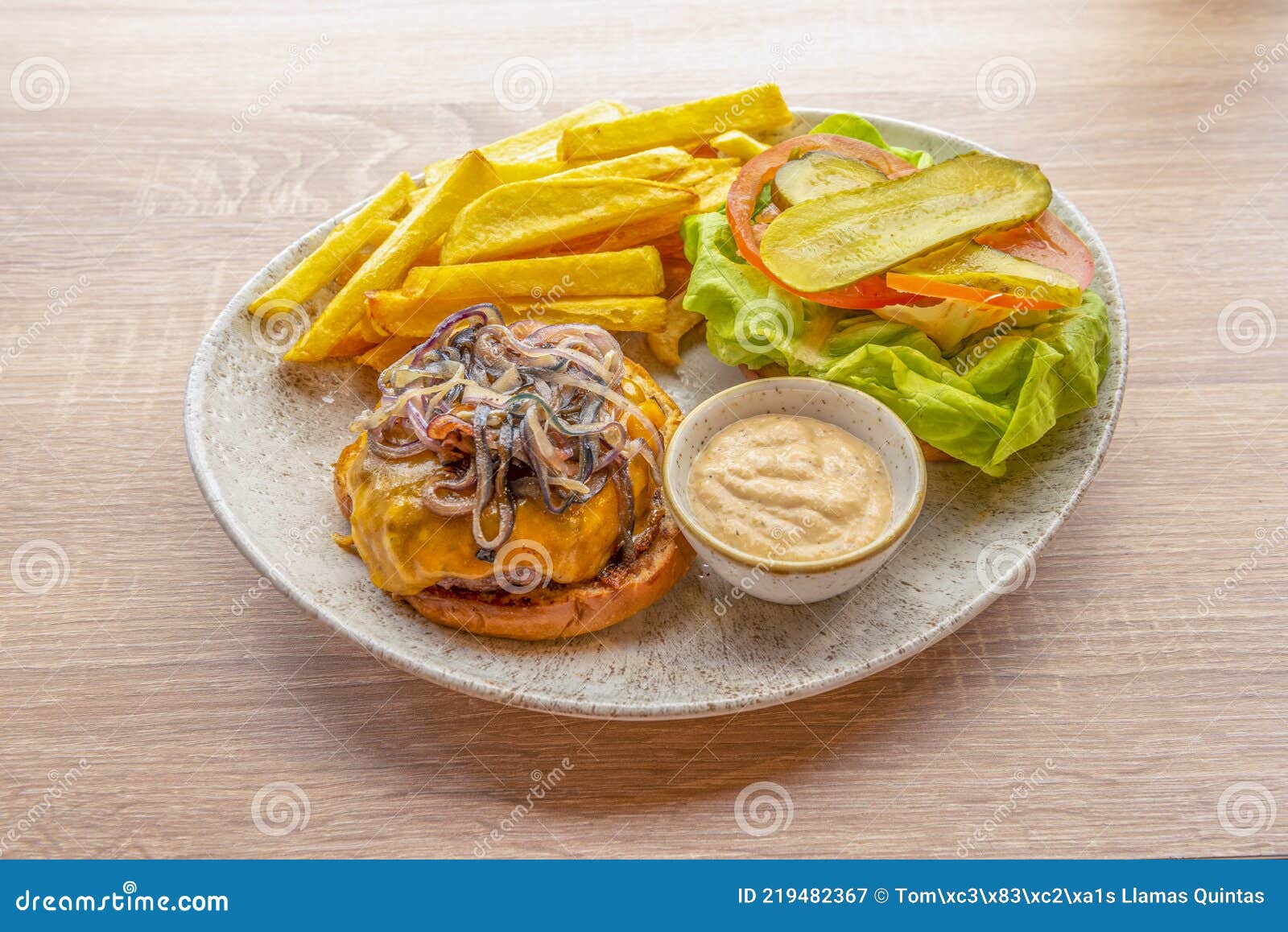 hamburguesa con salsa mayonesa, cebolla caramelizada, queso cheddar, patatas fritas, pepinillos, tomate y lechuga