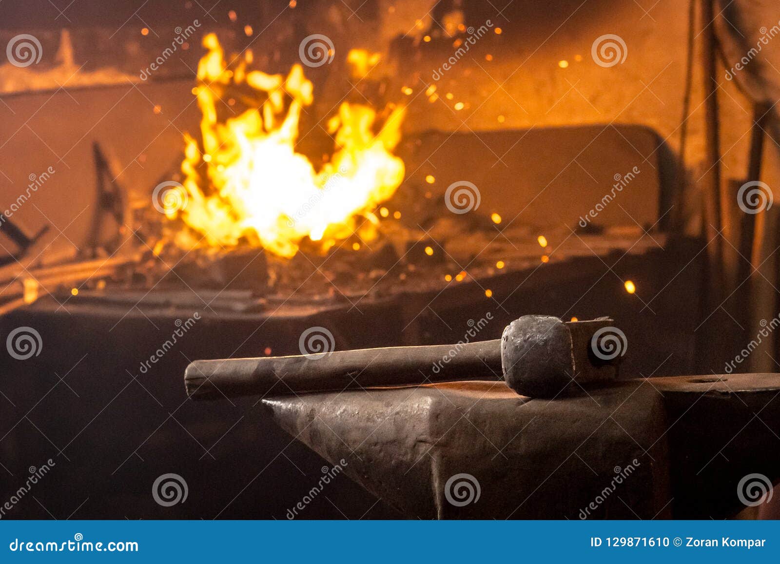 Hammer on Anvil with Fire of Burning Coal in Background Stock Photo