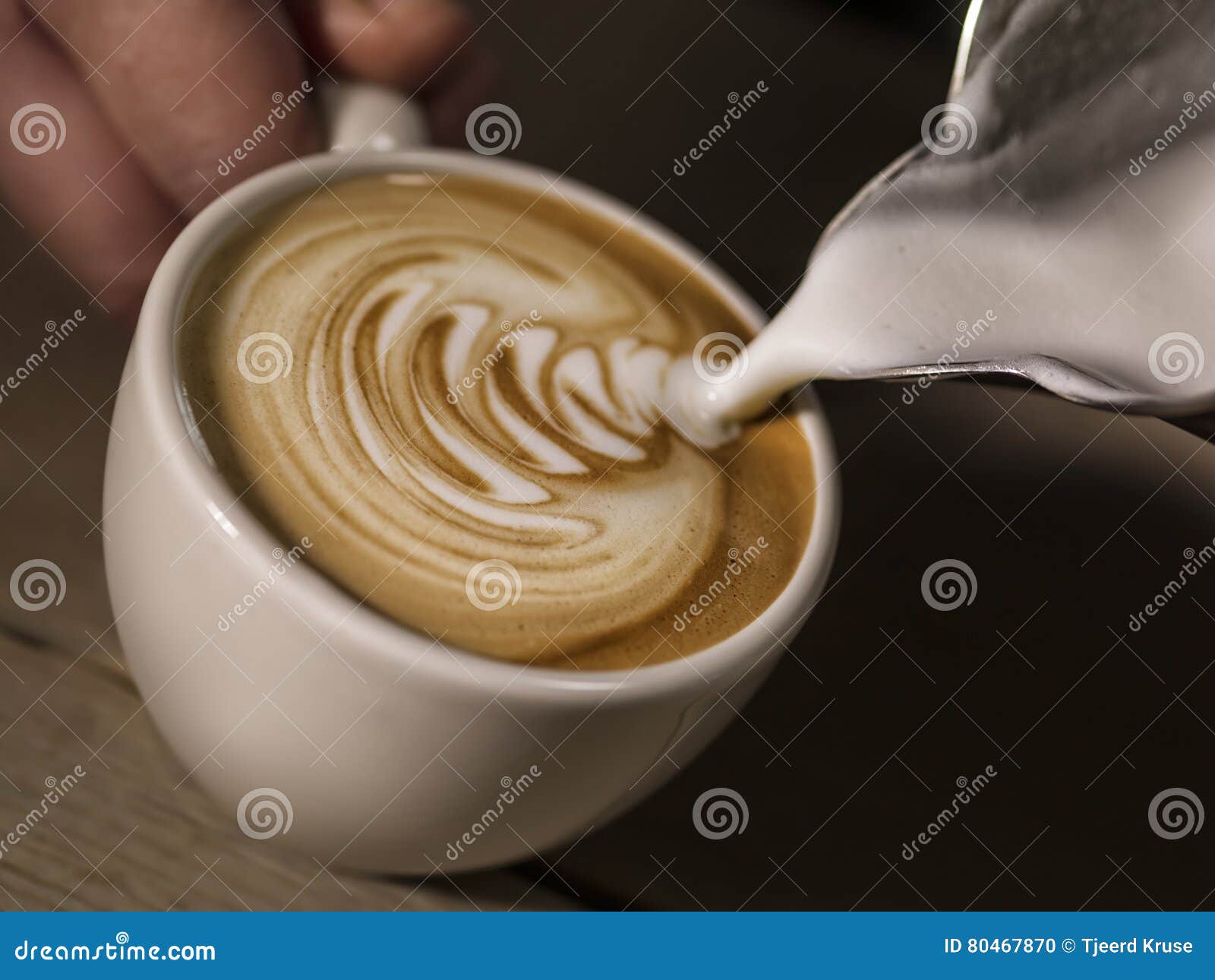 hand of barista making cappuccino coffee pouring milk making lat