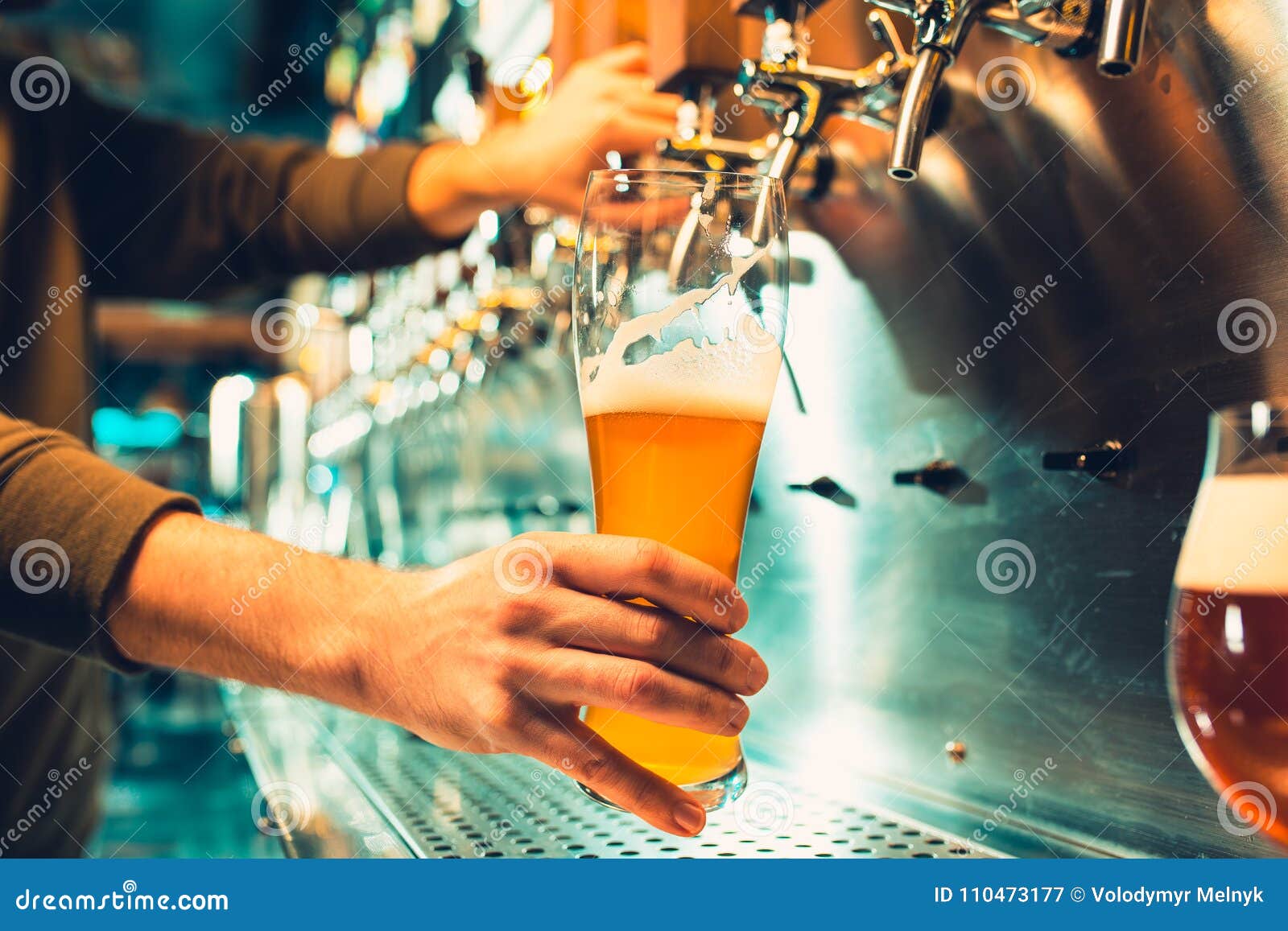 hand of bartender pouring a large lager beer in tap.
