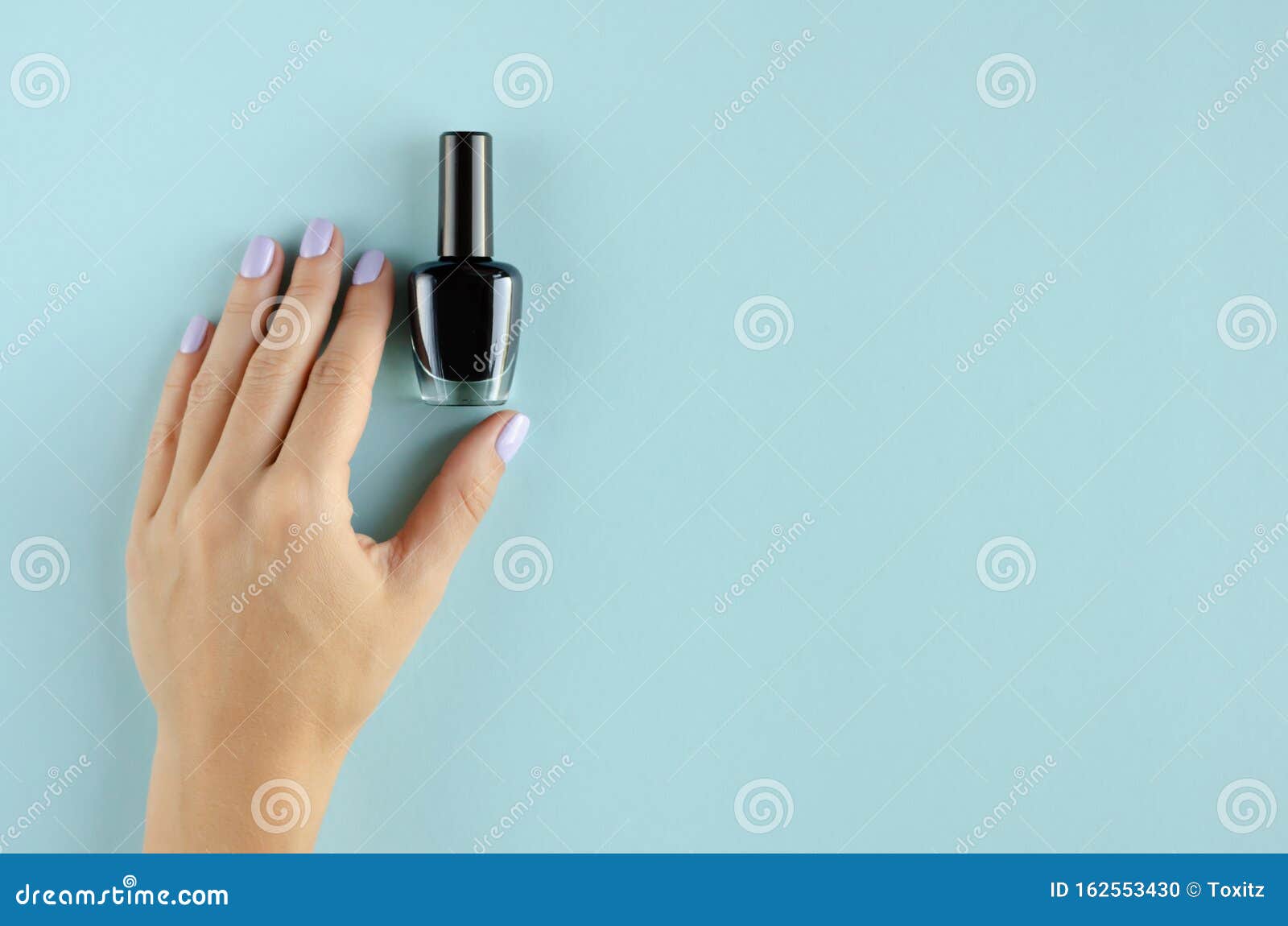 Hand with Black Nail Polish Composition on Blue Background Stock Photo