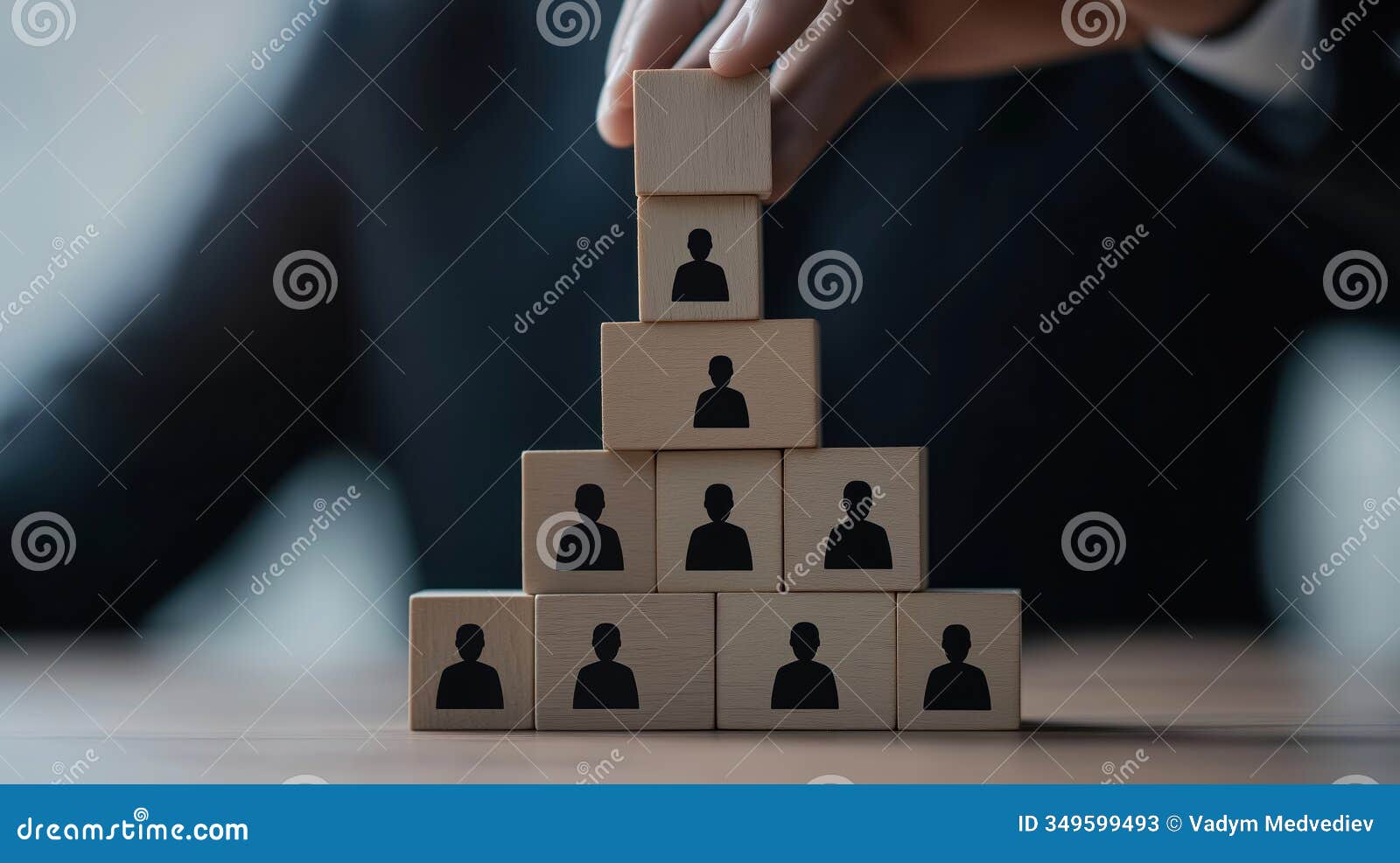 hand builds pyramid of wooden blocks with person icons. employee stock ownership plan visual representation. structure of legal