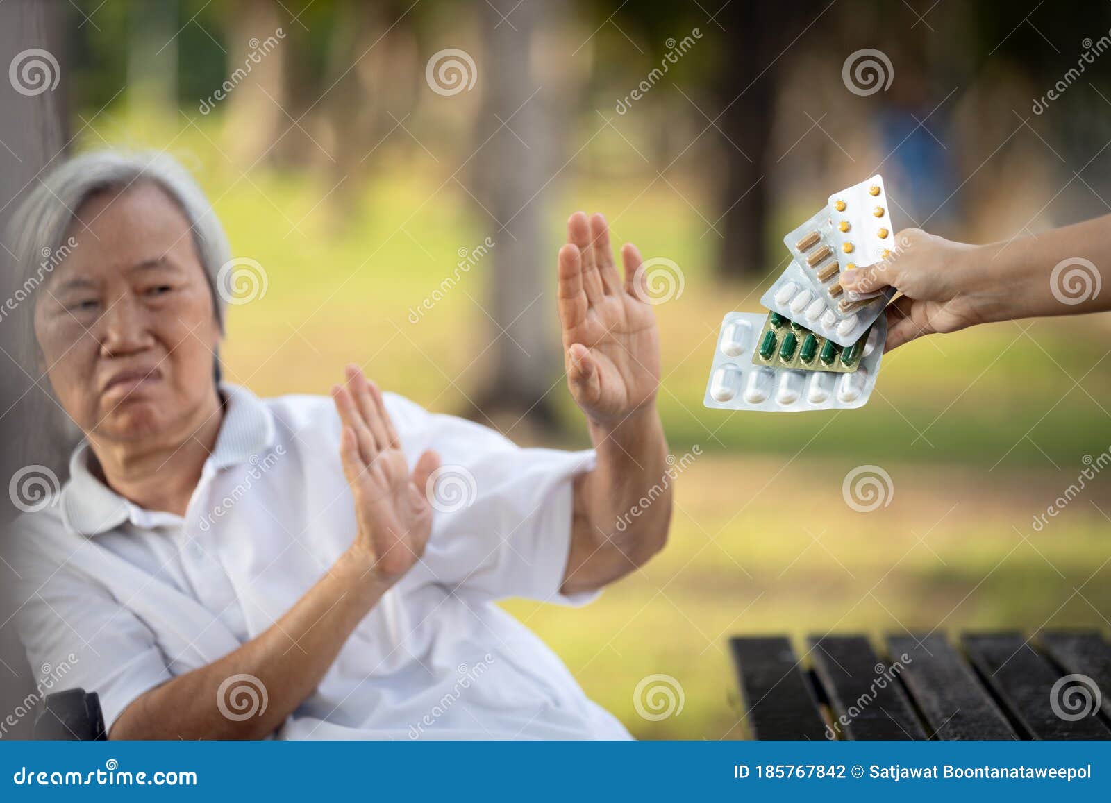 hand of caregiver giving medicine pills and capsules to the elderly,asian senior woman refusing to take medication,afraid,bad side