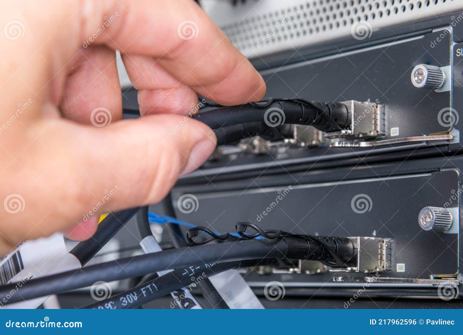 Hand of Computer Engineer Connecting Fiber Optic Cable in Server Stock