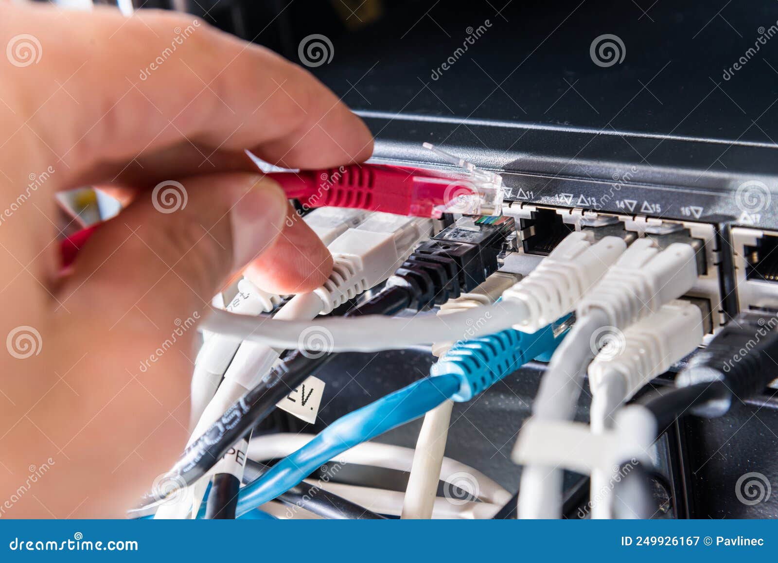 Hand of Computer Engineer Connecting Fiber Optic Cable in Server Stock